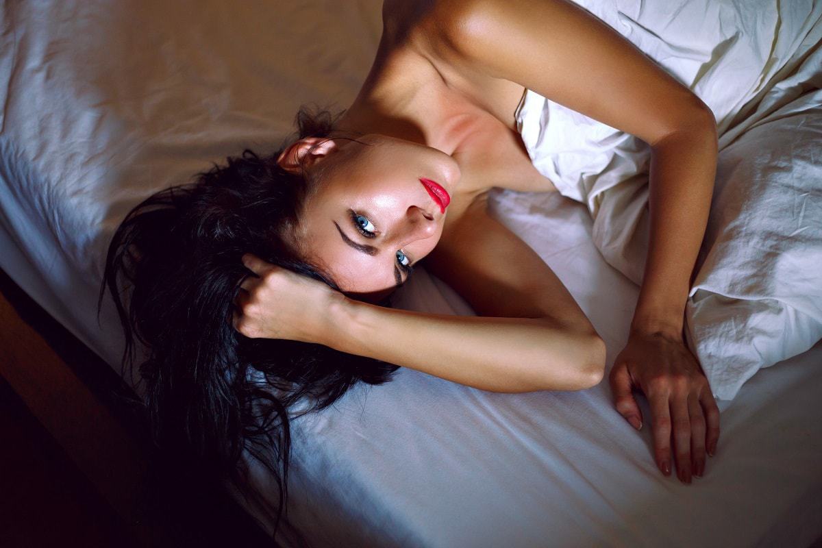 Sensual elegant woman brunette with long hair in bed