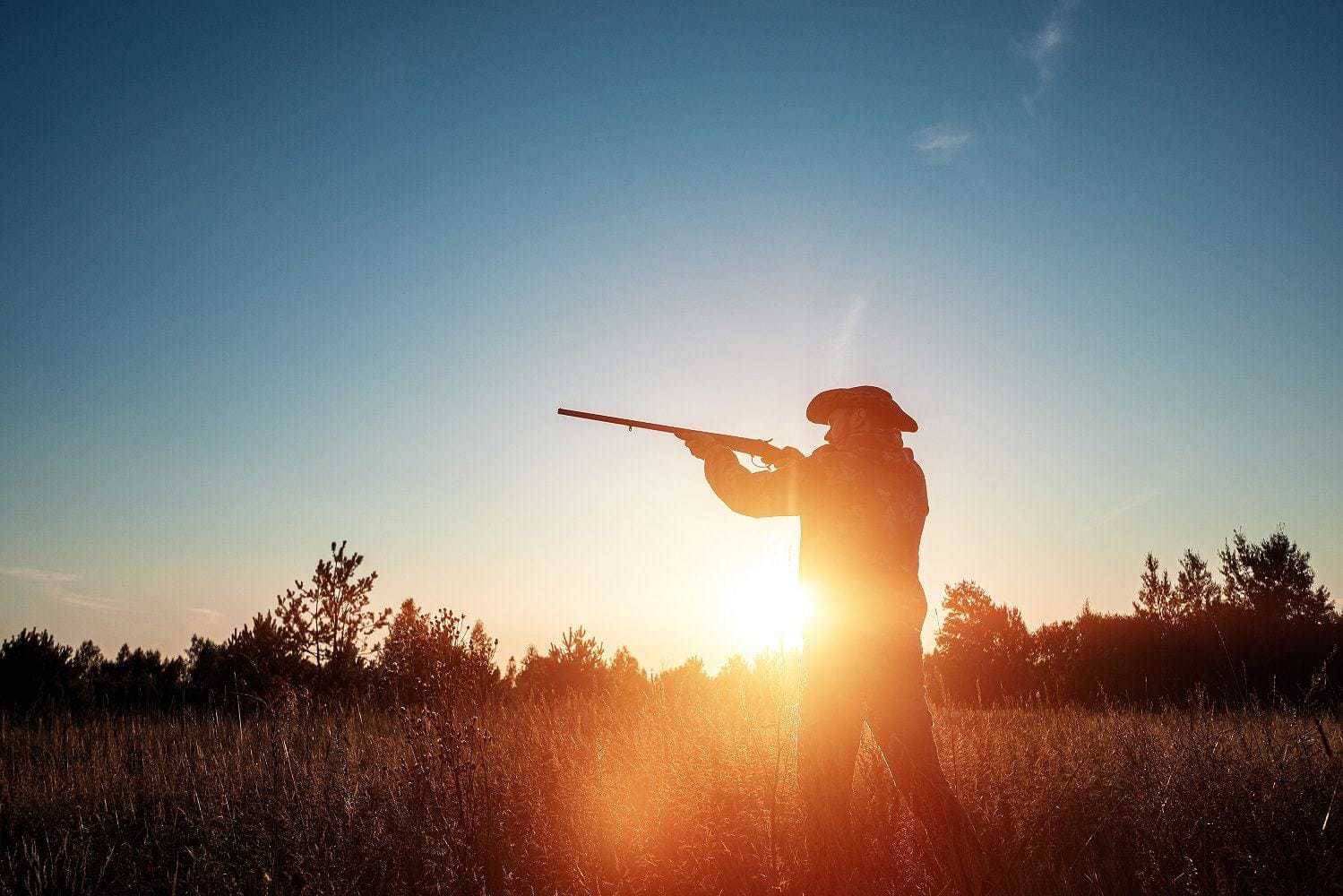 Hunter with hat and rifle in sunlight