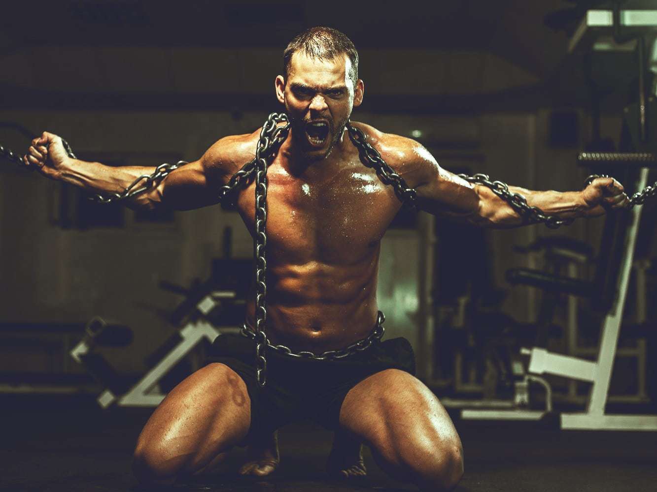 Muscular man in chains breaking free