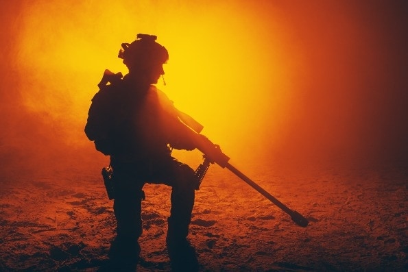 Army soldier with sniper rifle in fog