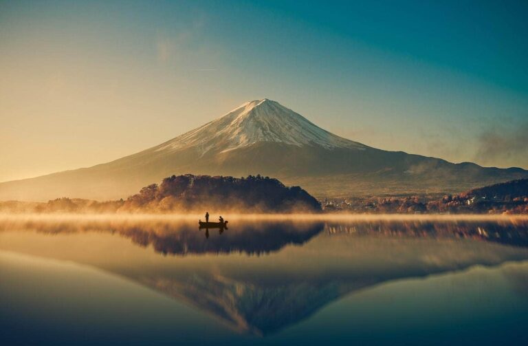 Boat on a silent lake in front of huge mountain