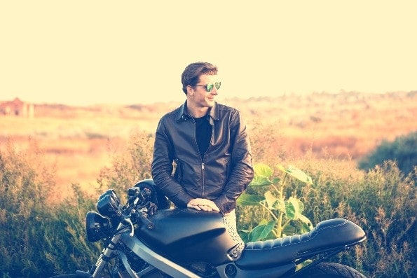 Handsome man standing next to motorcycle