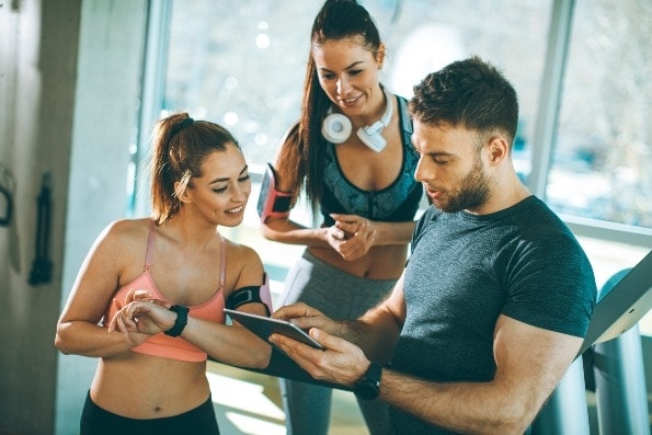 Handsome man talking to two hot women in the gym