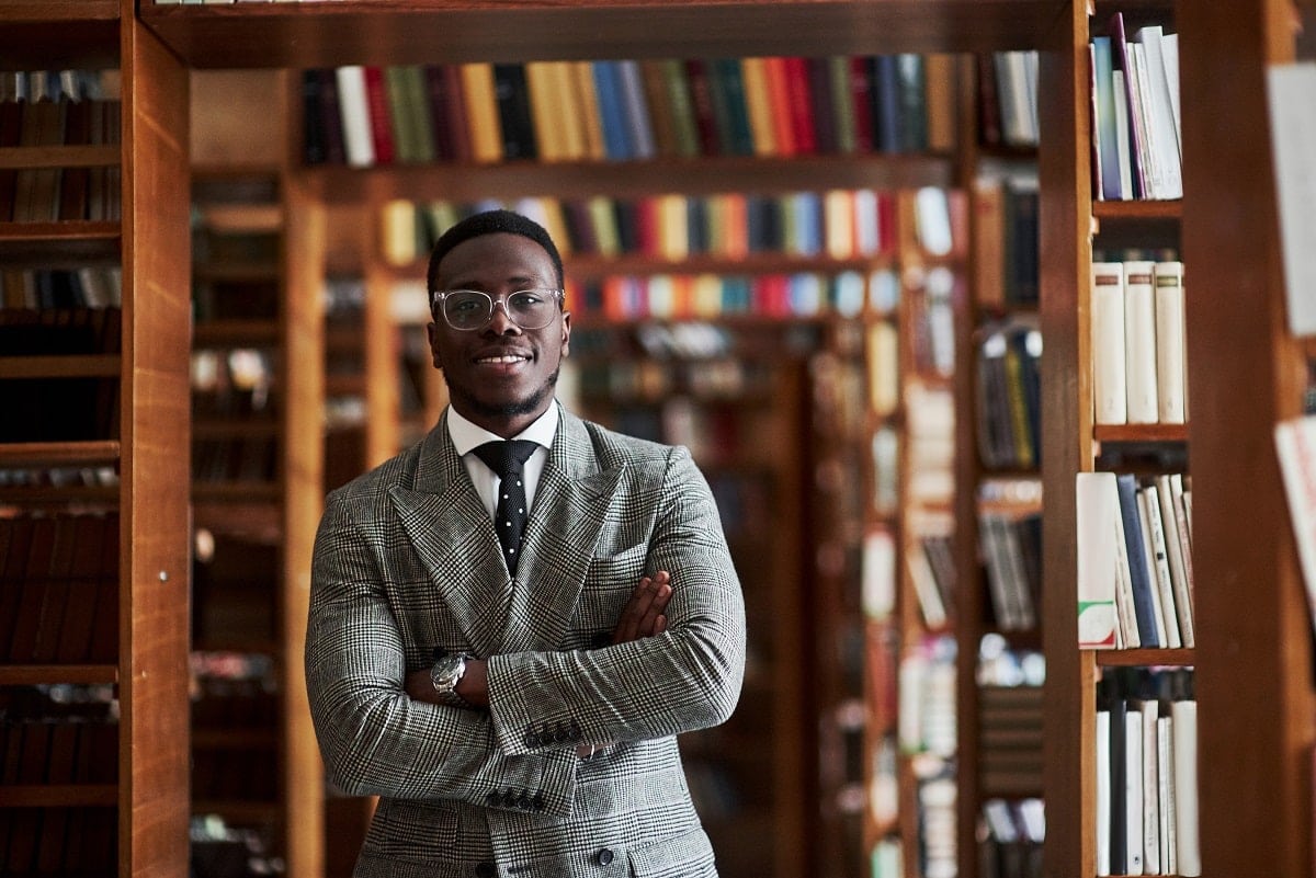 An African American man in a business suit standing in a library in the reading room.