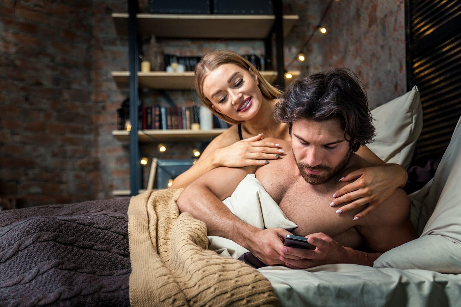 Couple in bed man cheating on phone